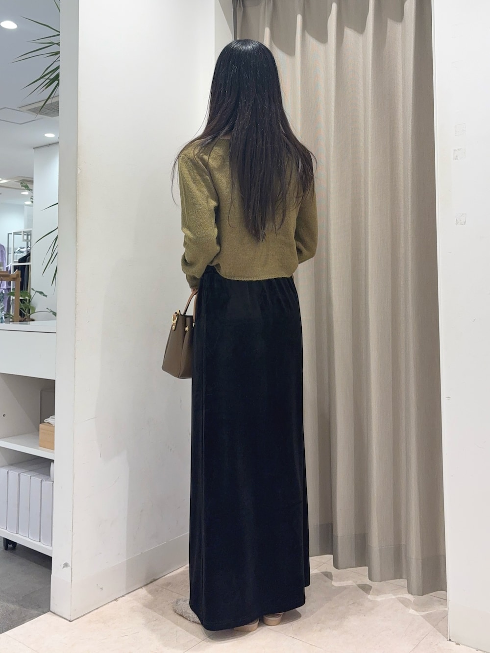 グリーン系のニット/セーター、ホワイト系のキャミソール、ブラウン系のスカートを着用したレディースの秋コーディネートの2枚目の写真