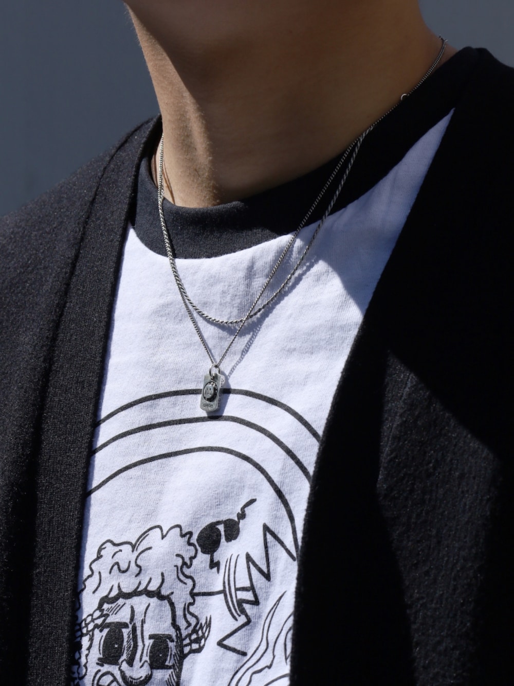 ブラック系のカーディガン/ボレロ、グレー系のスニーカー、ブラック系のデニムパンツを着用したメンズの春コーディネートの2枚目の写真