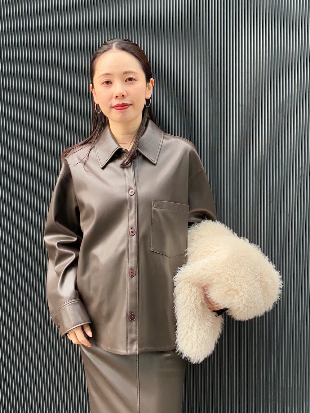 ホワイト系のベスト、ブラウン系のブルゾン、ブラウン系のスカートを着用したレディースの秋コーディネートの5枚目の写真