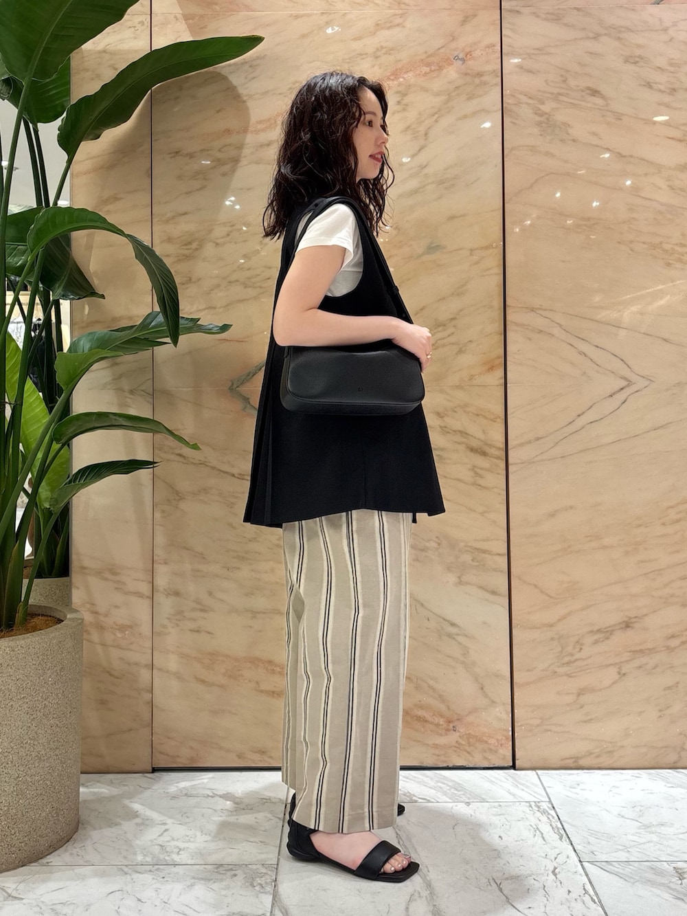 ブラック系のベスト、ベージュ系のその他パンツ、ブラック系のトートバッグを着用したレディースの夏コーディネートの2枚目の写真