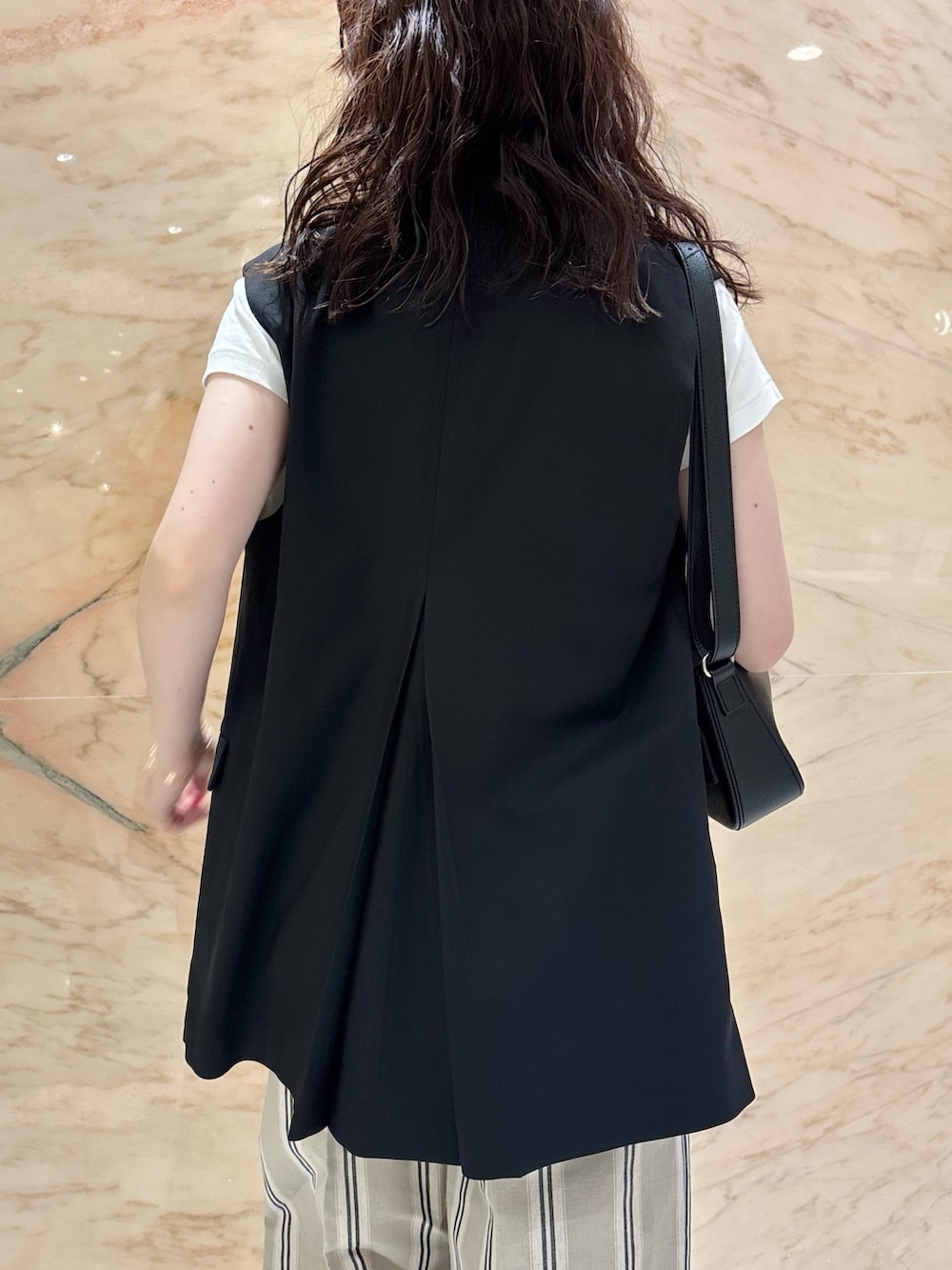 ブラック系のベスト、ベージュ系のその他パンツ、ブラック系のトートバッグを着用したレディースの夏コーディネートの4枚目の写真