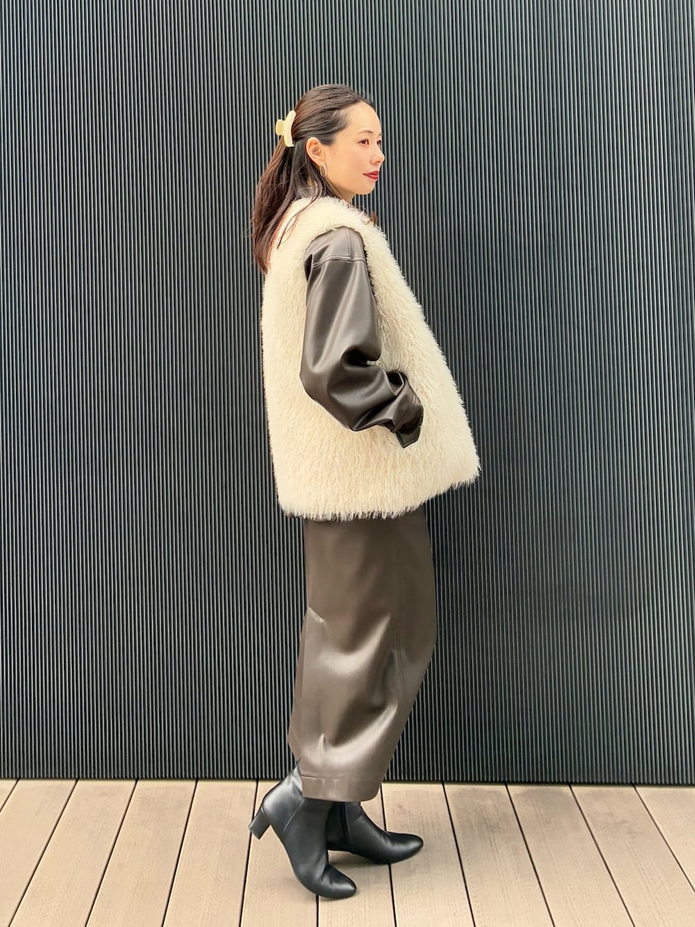 ホワイト系のベスト、ブラウン系のブルゾン、ブラウン系のスカートを着用したレディースの秋コーディネートの2枚目の写真