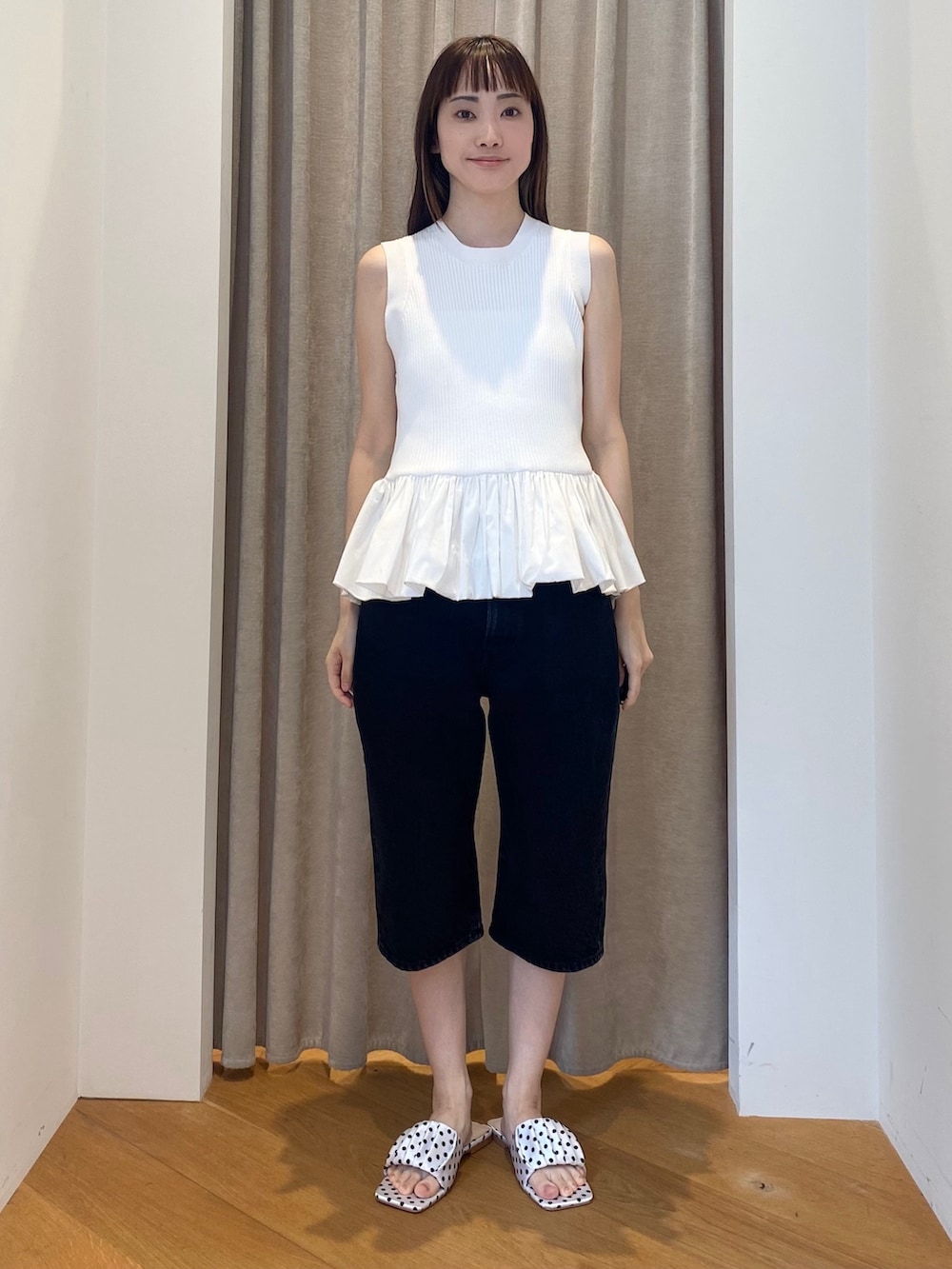 イエロー系のカーディガン/ボレロ、ホワイト系のニット/セーター、ブラック系のデニムパンツを着用したレディースの春コーディネートの2枚目の写真