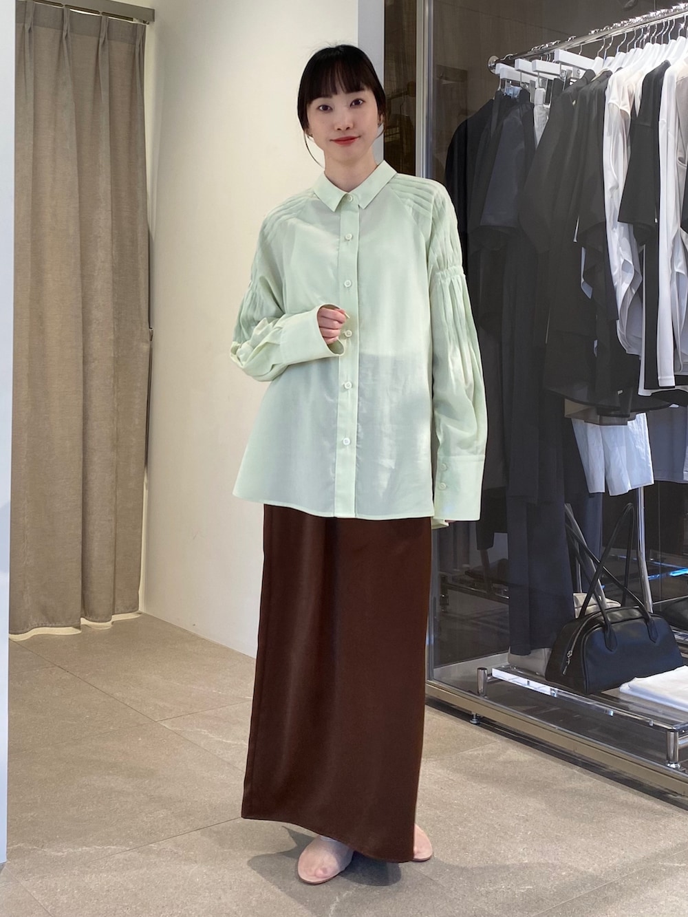 グリーン系のシャツ/ブラウス、ベージュ系のテーラードジャケット、ブラウン系のスカートを着用したレディースの冬コーディネートの2枚目の写真