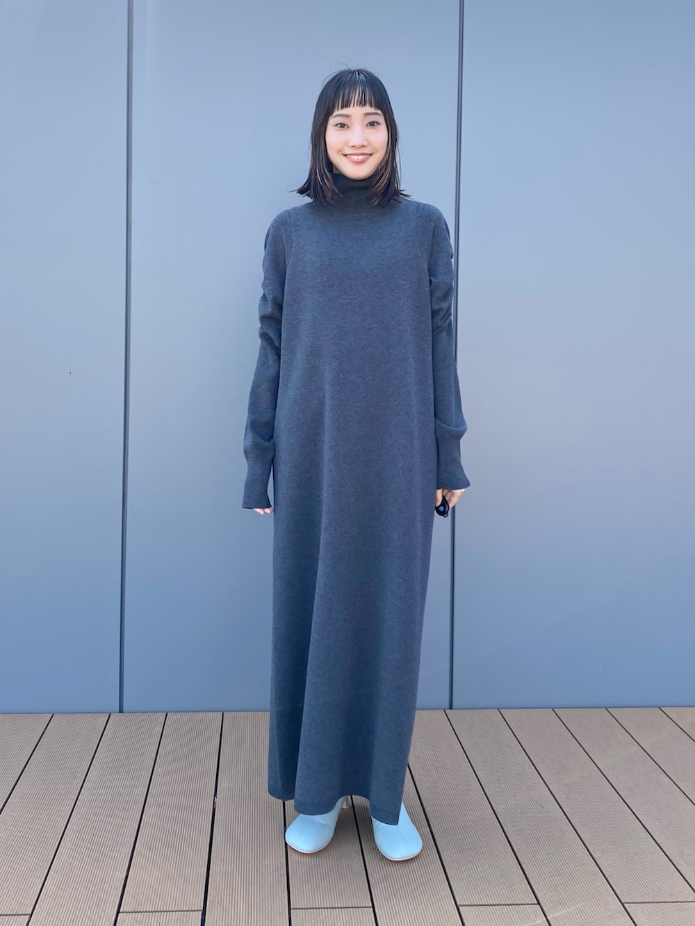 グレー系のワンピース、パープル系のカーディガン/ボレロ、ブルー系のパンプスを着用したレディースの秋コーディネートの2枚目の写真