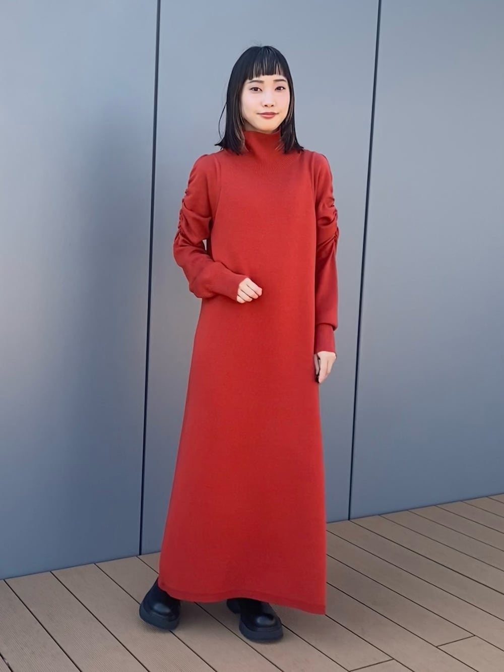 オレンジ系のワンピース、ホワイト系のブルゾン、グリーン系のボストンバッグを着用したレディースの秋コーディネートの2枚目の写真