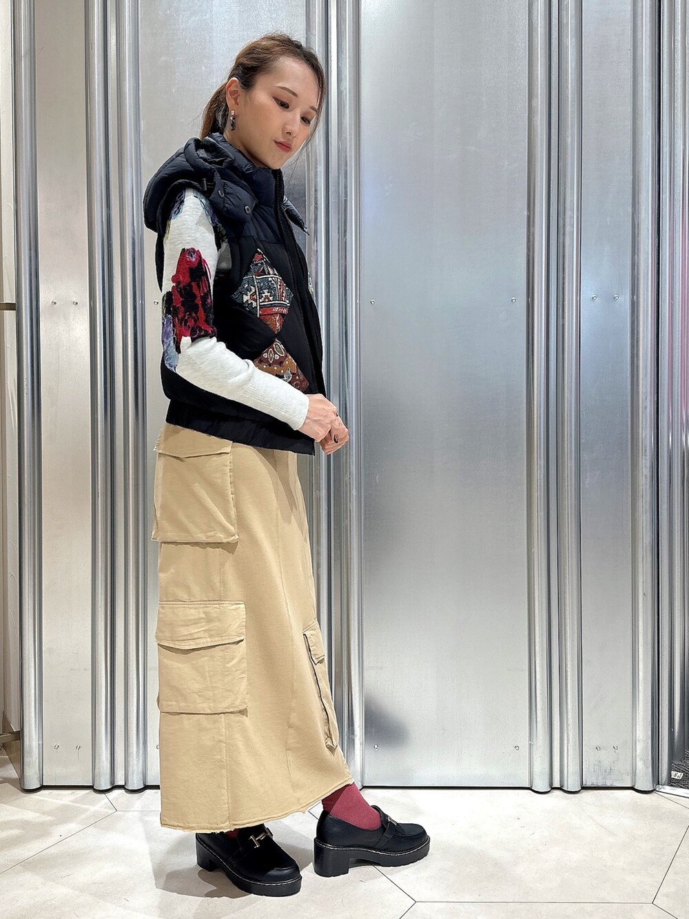 ブラウン系のスカート、ブルー系のダウンジャケット/コート、ブルー系のニット/セーターを着用したレディースの秋コーディネートの2枚目の写真