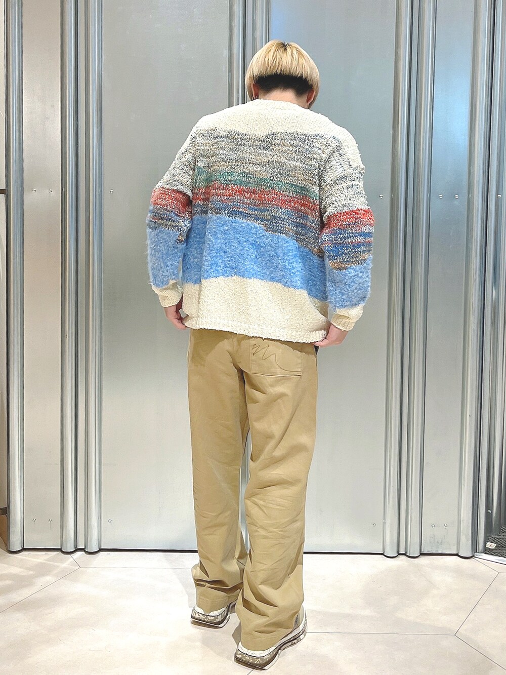 ブラウン系のスニーカー、その他のニット/セーター、ブラウン系のチノパンツを着用したメンズの秋コーディネートの3枚目の写真