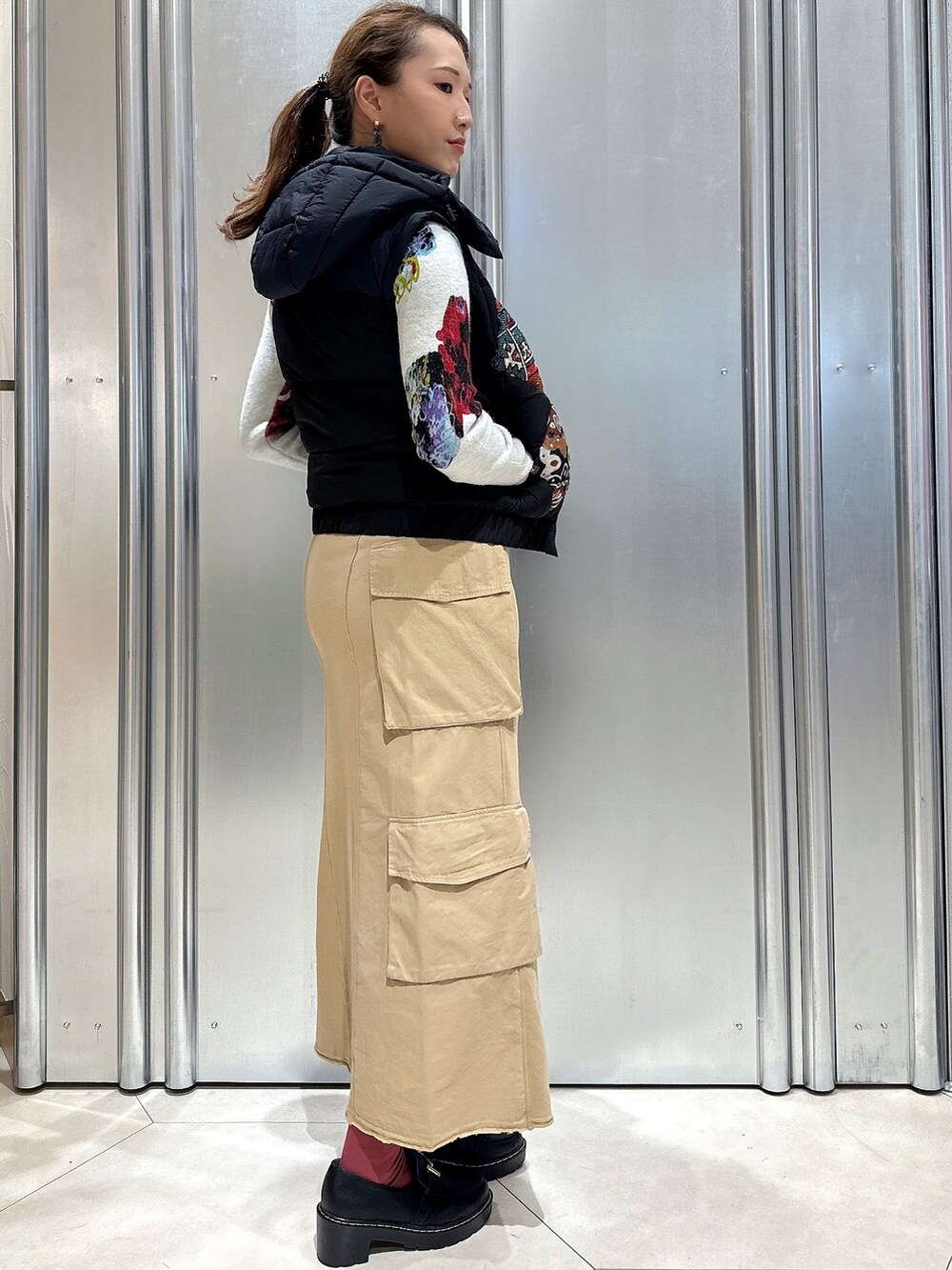 ブラウン系のスカート、ブルー系のダウンジャケット/コート、ブルー系のニット/セーターを着用したレディースの秋コーディネートの3枚目の写真