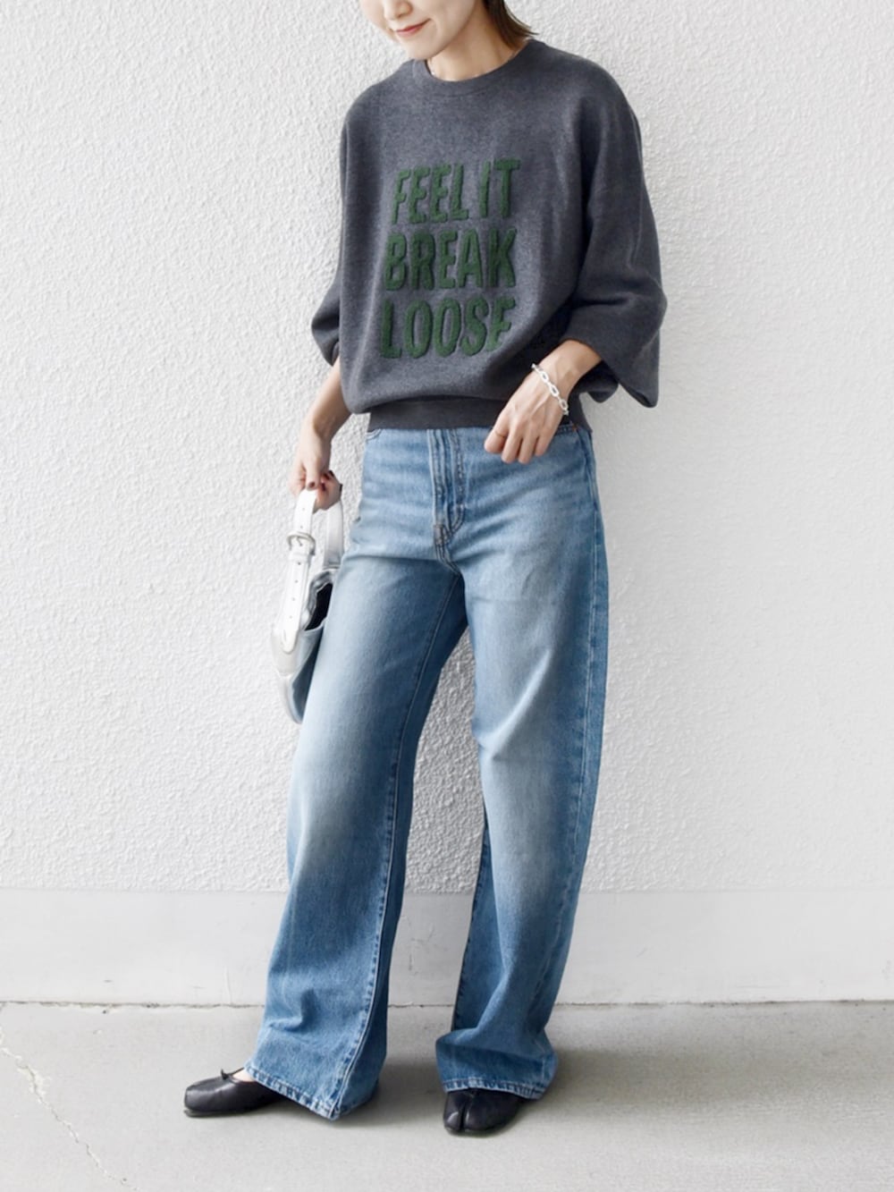 ブルー系のデニムパンツ、グレー系のニット/セーターを着用したレディースの秋コーディネートの2枚目の写真