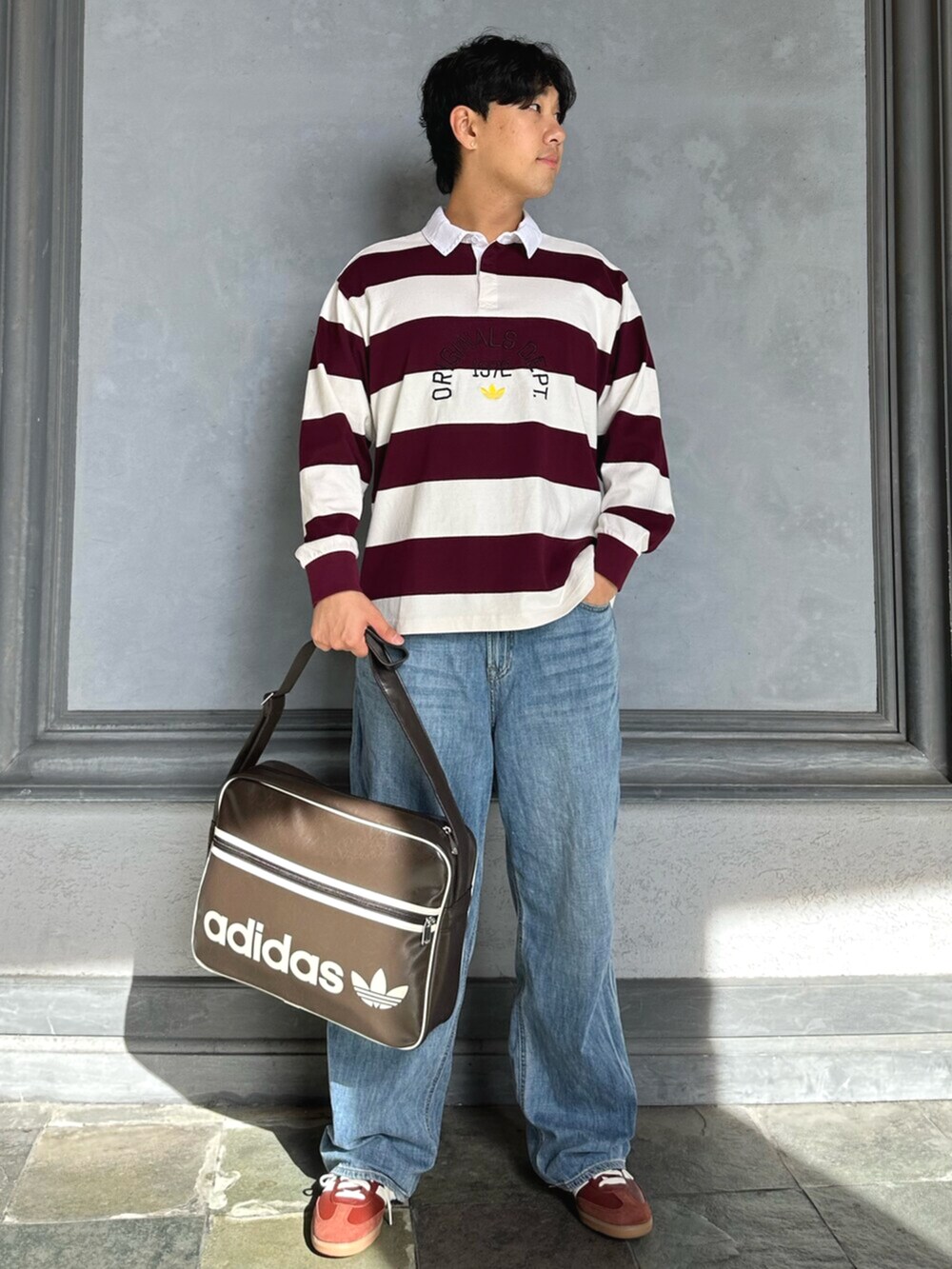 ホワイト系のポロシャツ、ブラウン系のバッグ、ブラウン系のスニーカーを着用したメンズの秋コーディネートの2枚目の写真