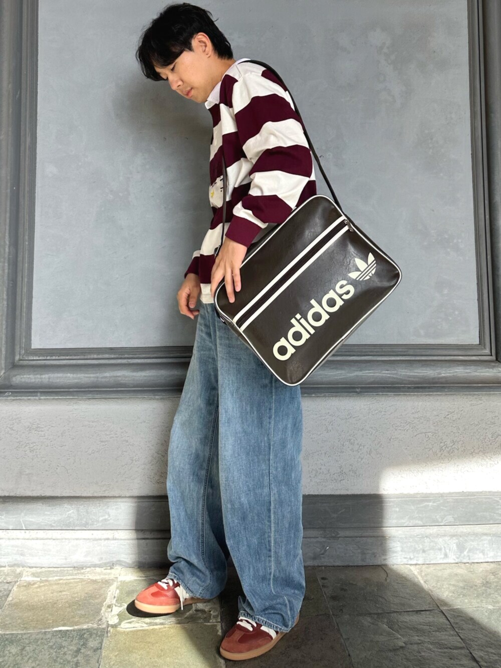 ホワイト系のポロシャツ、ブラウン系のバッグ、ブラウン系のスニーカーを着用したメンズの秋コーディネートの3枚目の写真