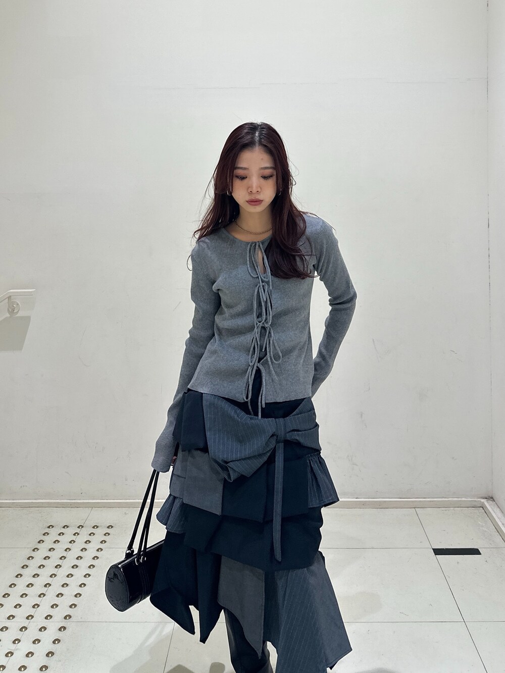 グレー系のニット/セーター、その他のスカート、ブラック系のブーツを着用したレディースの冬コーディネートの2枚目の写真