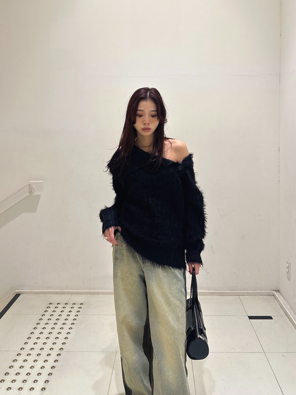 ブルー系のデニムパンツ、ブラック系のショルダーバッグ、ブラック系のブーツを着用したレディースの冬コーディネートの2枚目の写真