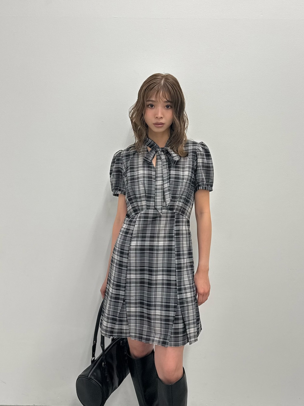 ブラック系のワンピース、ブラック系のブーツ、ブラック系のハンドバッグを着用したレディースの夏コーディネートの3枚目の写真
