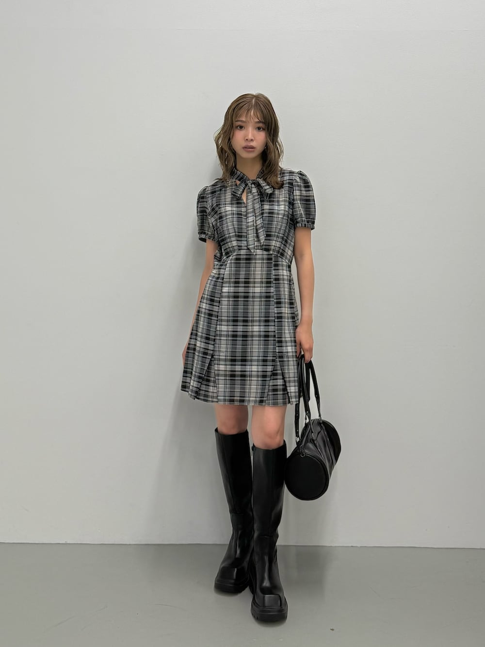 ブラック系のワンピース、ブラック系のブーツ、ブラック系のハンドバッグを着用したレディースの夏コーディネートの2枚目の写真