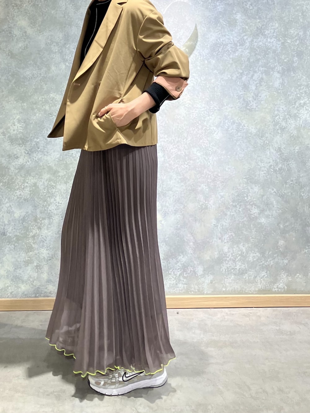 ブラック系のニット/セーター、ブラウン系のテーラードジャケット、グリーン系のスカートを着用したレディースの秋コーディネートの2枚目の写真