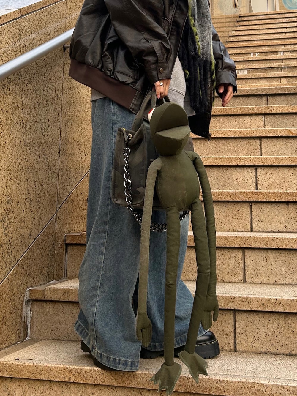 グレー系のスウェット、ブラウン系のライダースジャケット、ブルー系のデニムパンツを着用したレディースの秋コーディネートの2枚目の写真