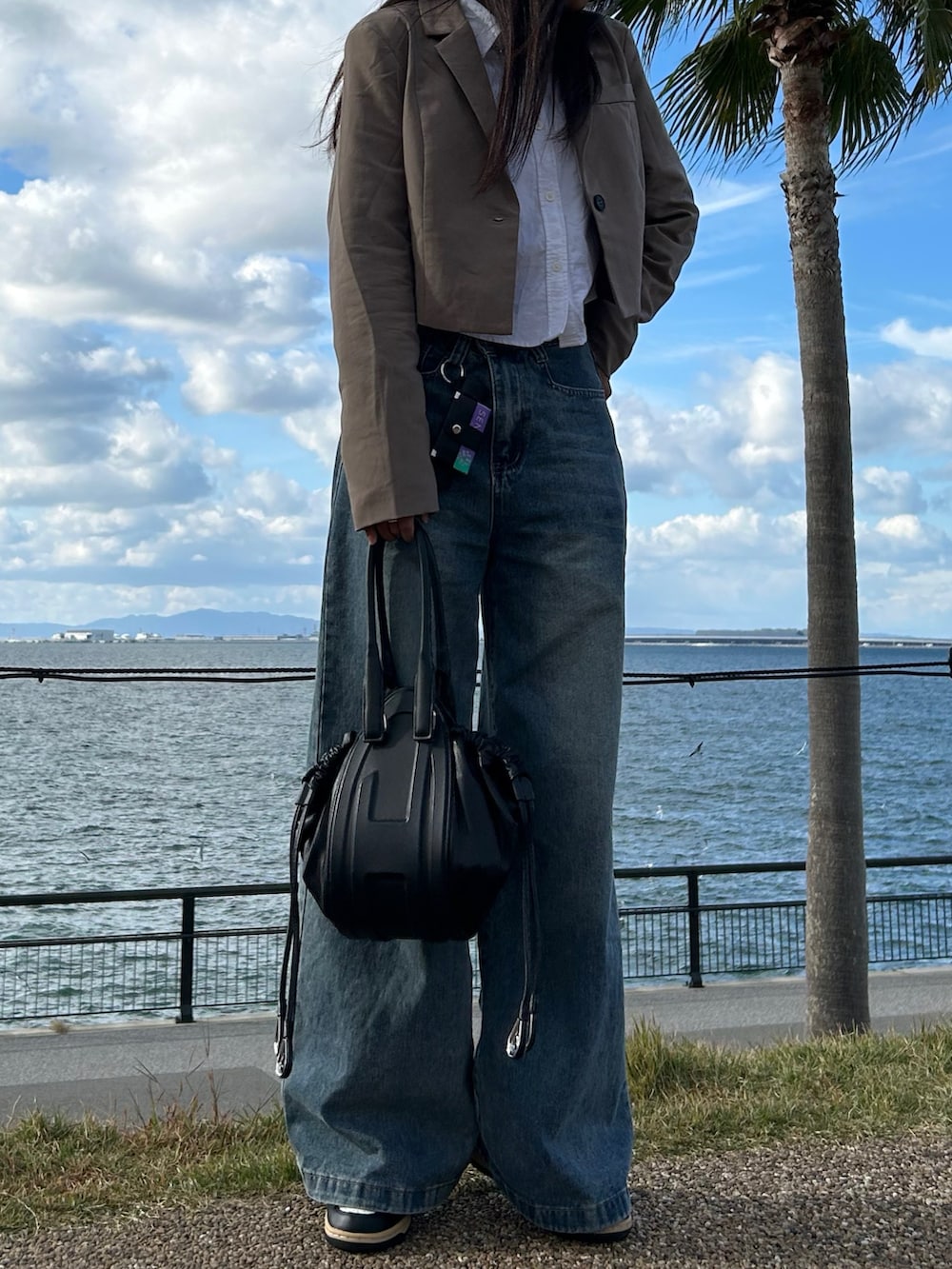ブルー系のデニムパンツ、ブラック系のハンドバッグ、ホワイト系のシャツ/ブラウスを着用したレディースの秋コーディネートの3枚目の写真