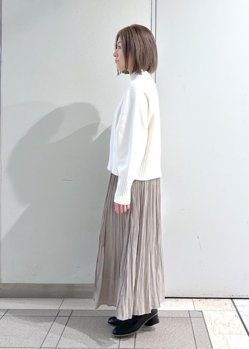 ホワイト系のニット/セーター、ブラック系のブーツ、ブラウン系のスカートを着用したレディースの冬コーディネートの6枚目の写真