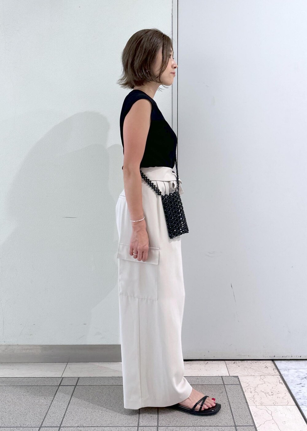 ブラック系のサンダル、ブラック系のニット/セーター、ブラック系のショルダーバッグを着用したレディースの夏コーディネートの4枚目の写真