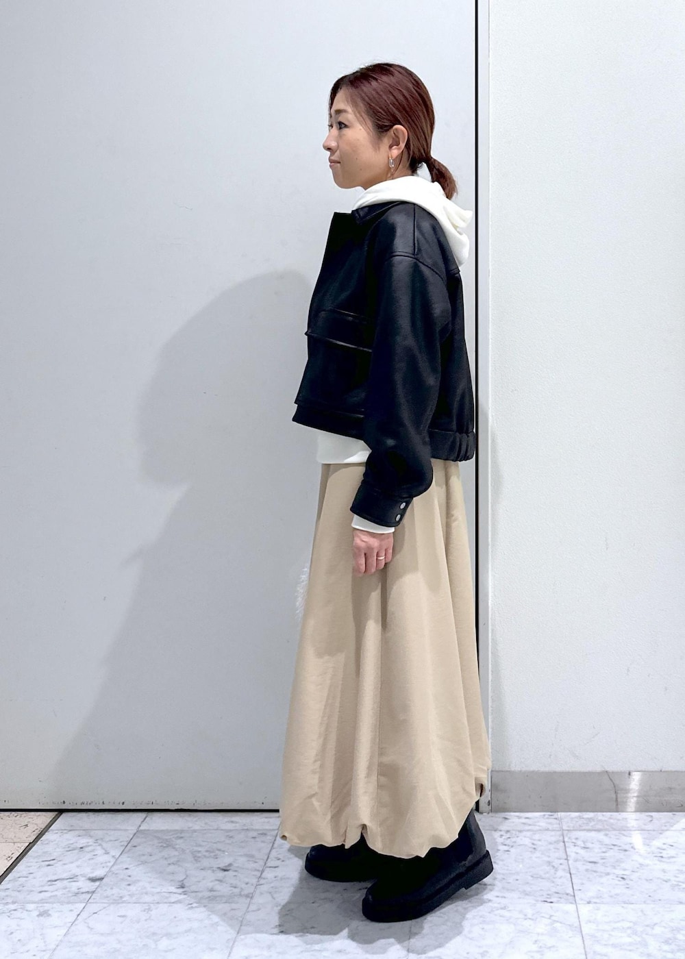 ベージュ系のハンドバッグ、ブラック系のブーツ、イエロー系のスカートを着用したレディースの秋コーディネートの2枚目の写真