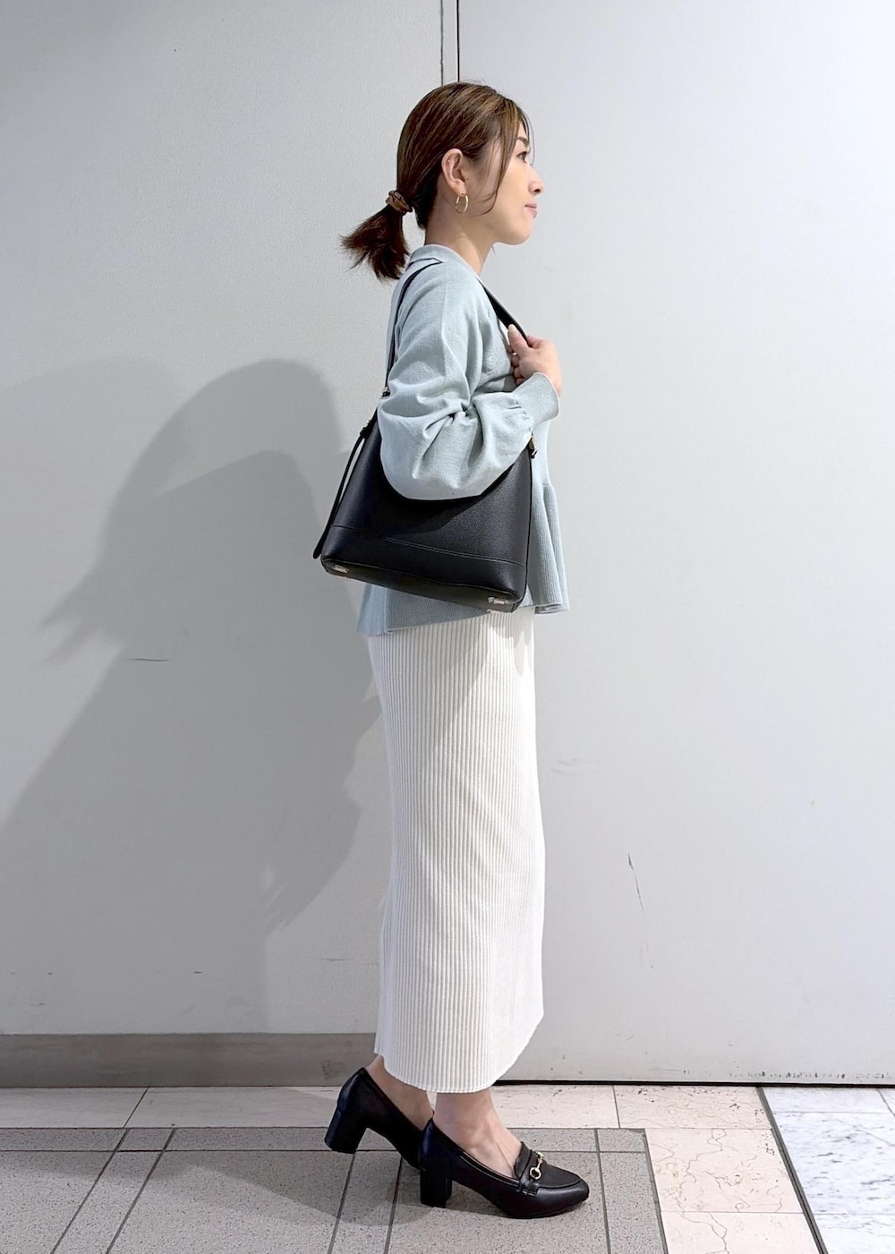 ブラック系のショルダーバッグ、ブラック系のローファー、ホワイト系のスカートを着用したレディースの春コーディネートの4枚目の写真