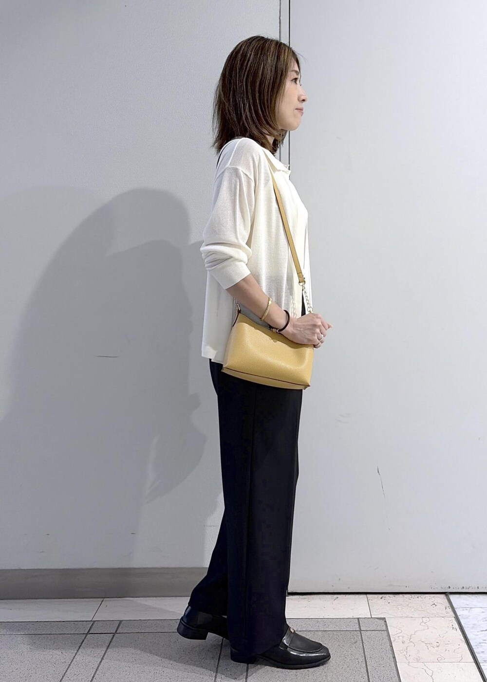 ブラウン系のショルダーバッグ、ブラック系のローファー、ブラック系のその他パンツを着用したレディースの春コーディネートの4枚目の写真