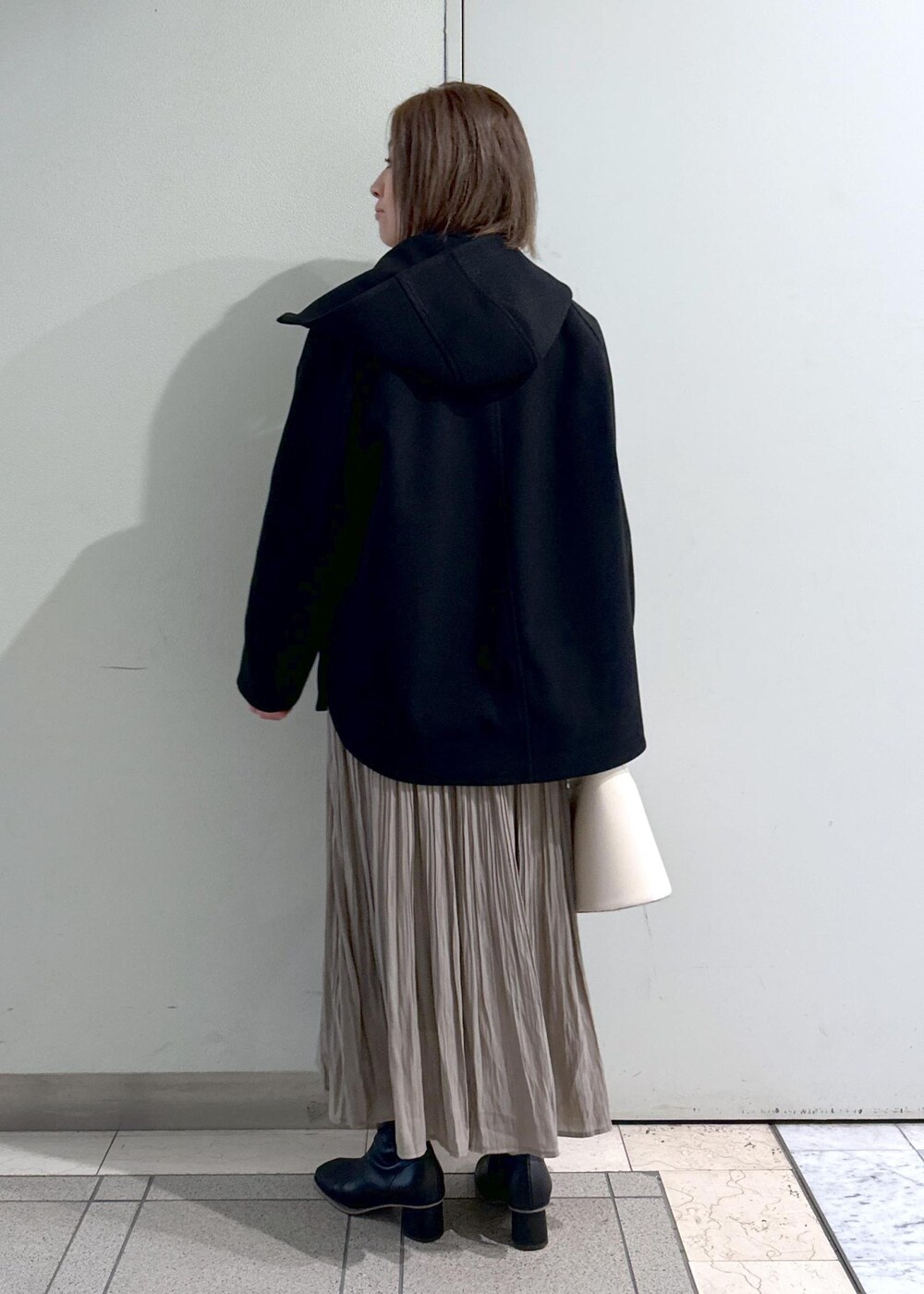 ホワイト系のニット/セーター、ブラック系のブーツ、ブラウン系のスカートを着用したレディースの冬コーディネートの3枚目の写真