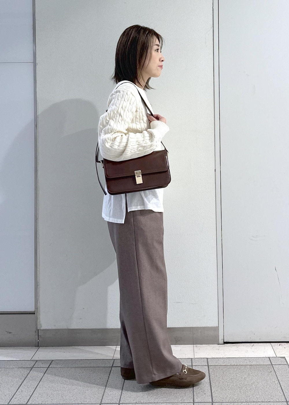 レッド系のショルダーバッグ、ベージュ系のスラックス、ホワイト系のTシャツ/カットソーを着用したレディースの冬コーディネートの4枚目の写真