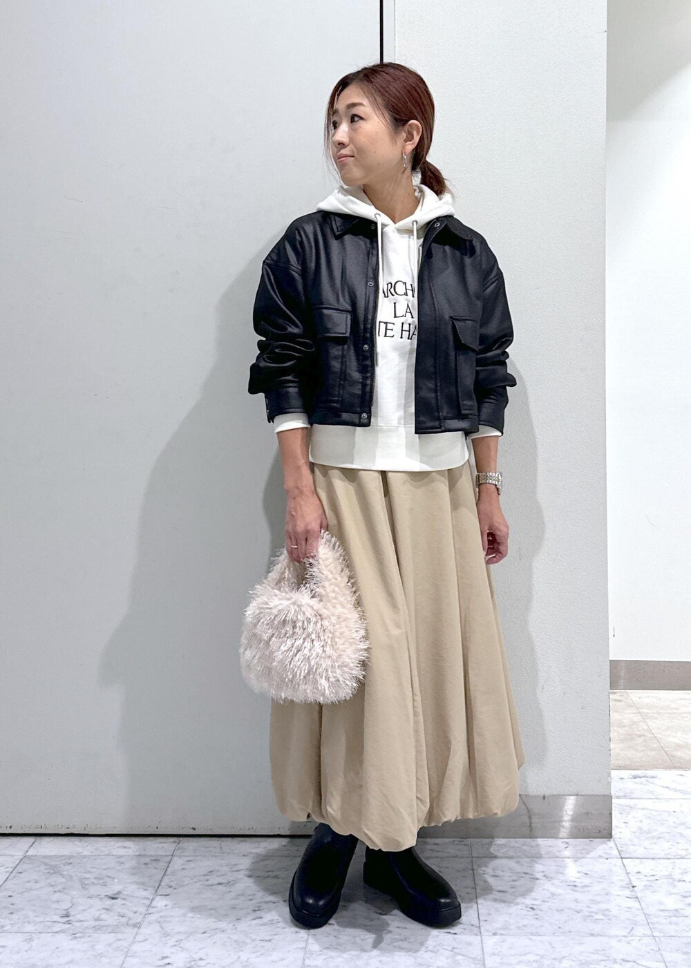 ベージュ系のハンドバッグ、ブラック系のブーツ、イエロー系のスカートを着用したレディースの秋コーディネートの5枚目の写真