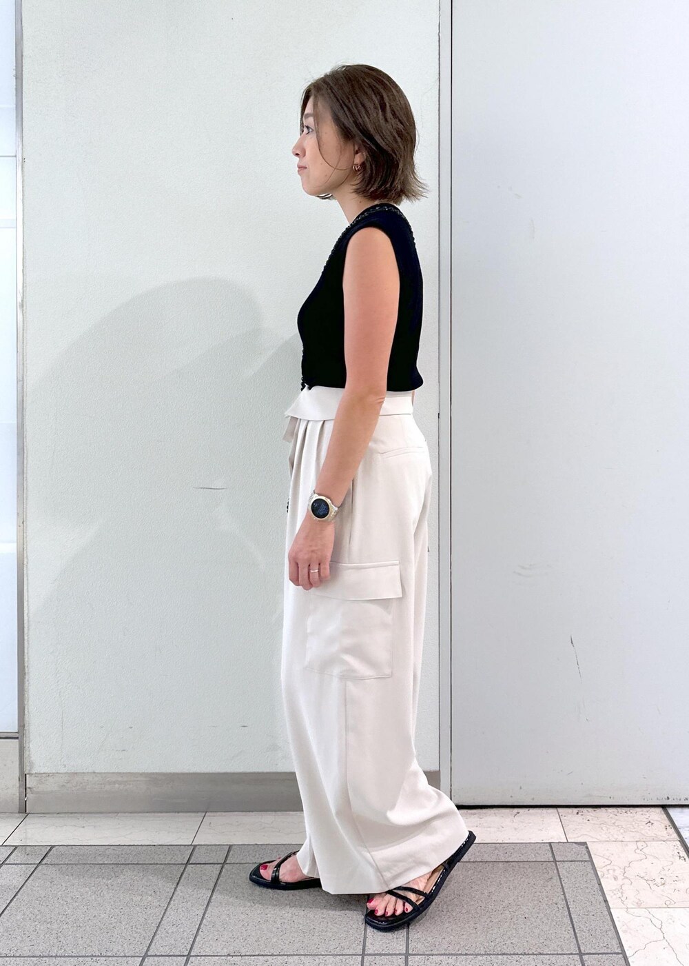 ブラック系のサンダル、ブラック系のニット/セーター、ブラック系のショルダーバッグを着用したレディースの夏コーディネートの2枚目の写真