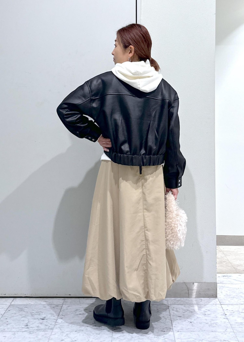 ベージュ系のハンドバッグ、ブラック系のブーツ、イエロー系のスカートを着用したレディースの秋コーディネートの3枚目の写真