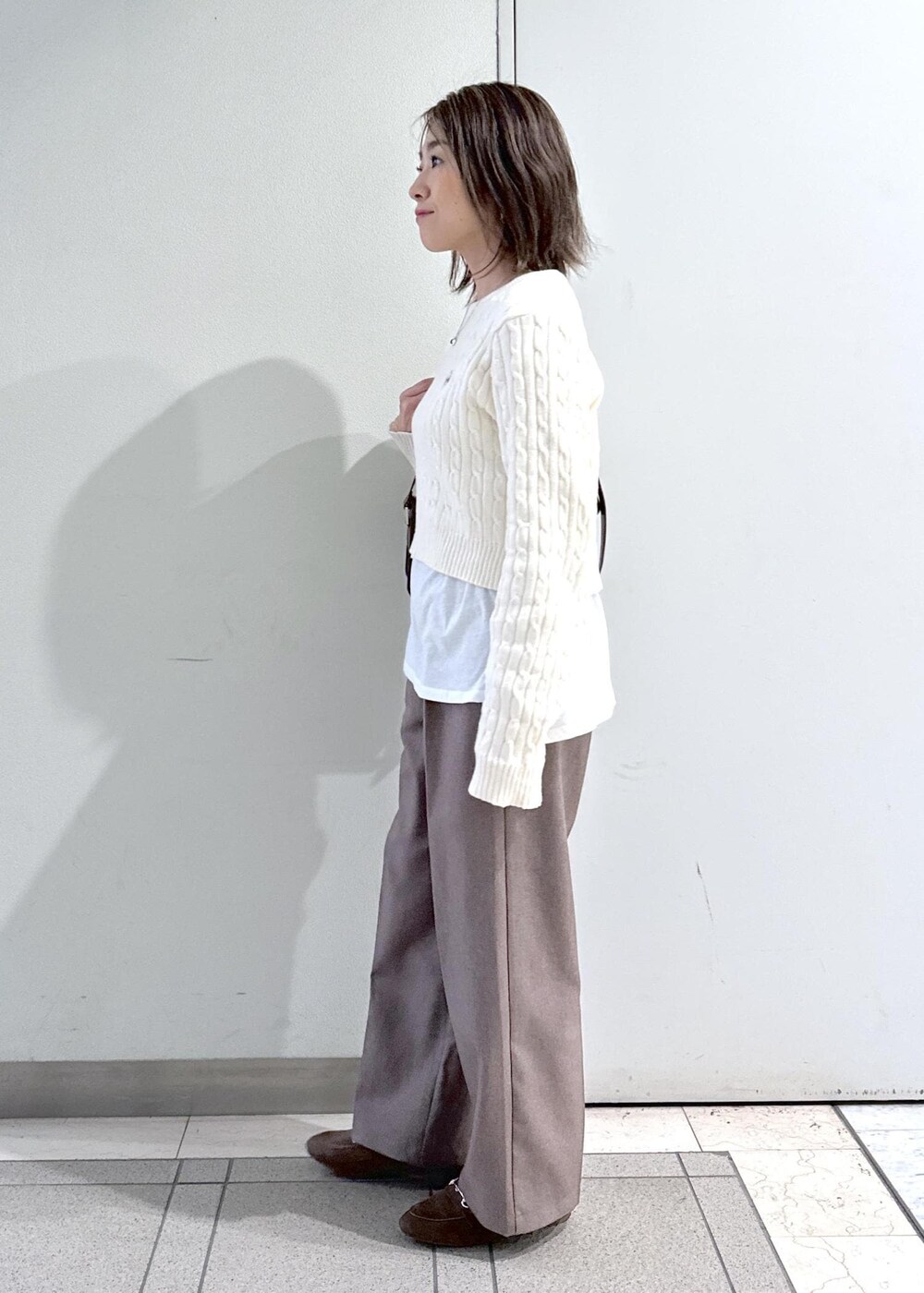 レッド系のショルダーバッグ、ベージュ系のスラックス、ホワイト系のTシャツ/カットソーを着用したレディースの冬コーディネートの2枚目の写真