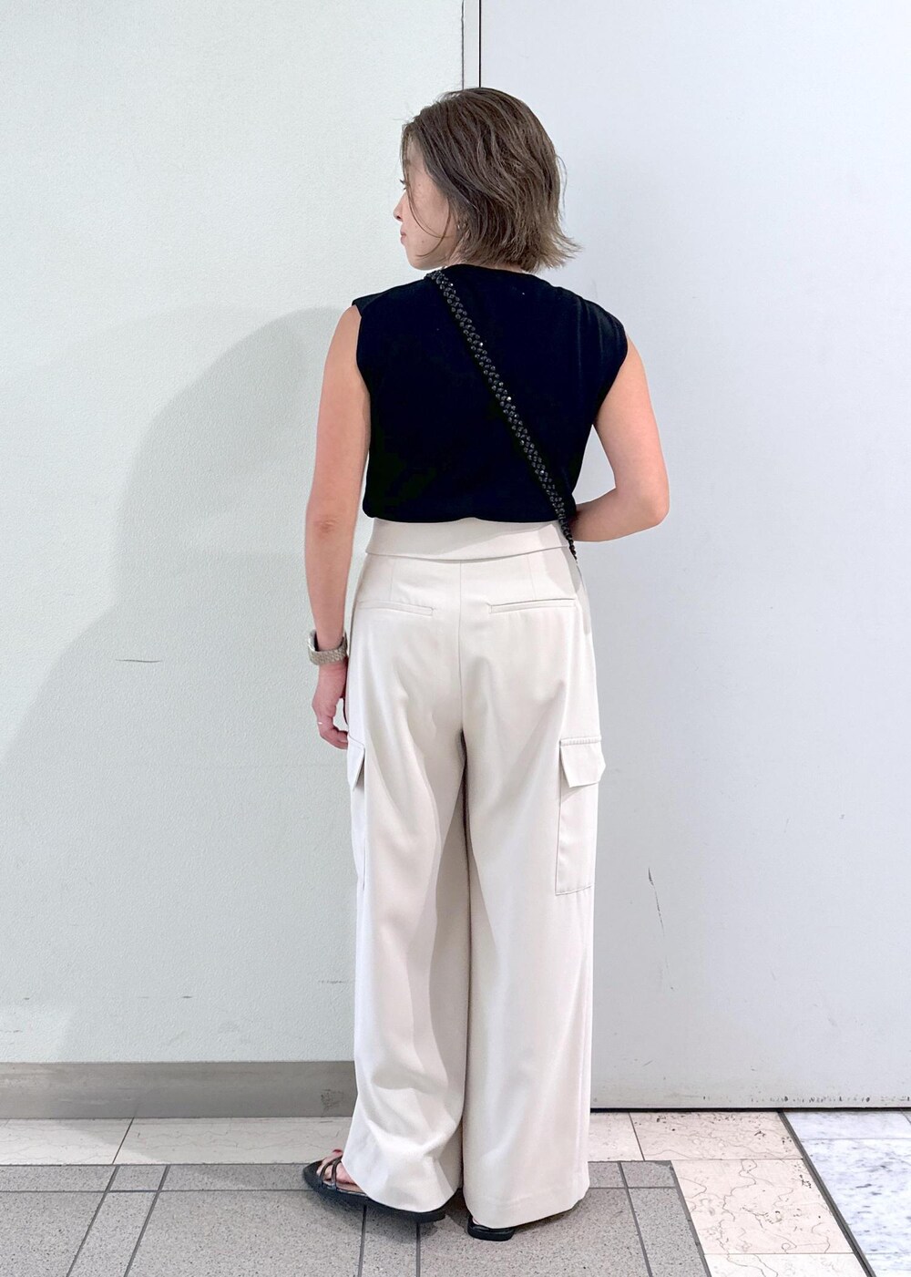 ブラック系のサンダル、ブラック系のニット/セーター、ブラック系のショルダーバッグを着用したレディースの夏コーディネートの3枚目の写真