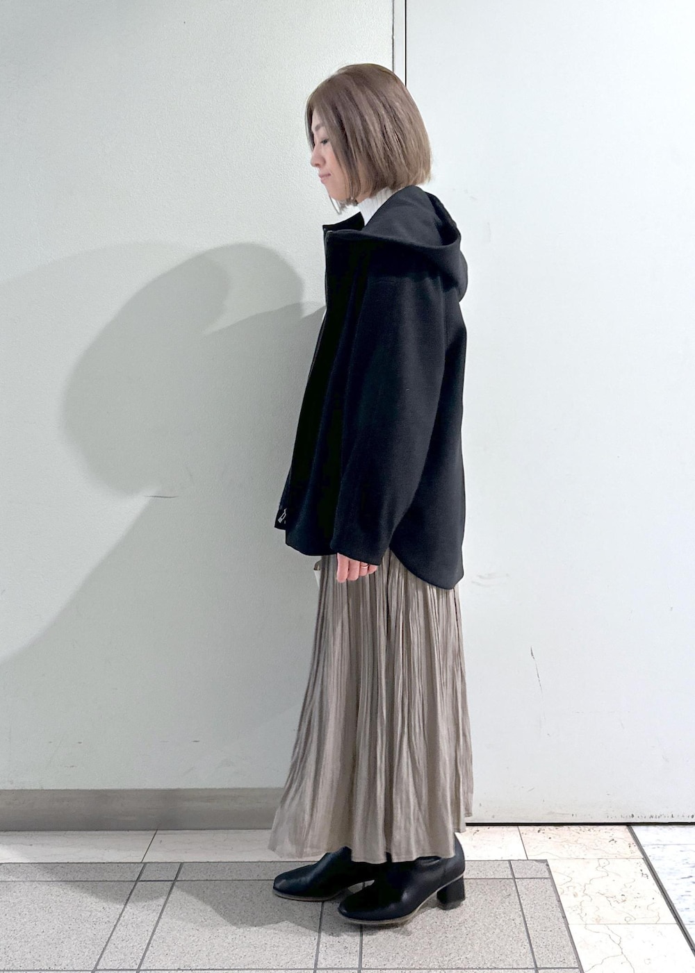 ホワイト系のニット/セーター、ブラック系のブーツ、ブラウン系のスカートを着用したレディースの冬コーディネートの2枚目の写真