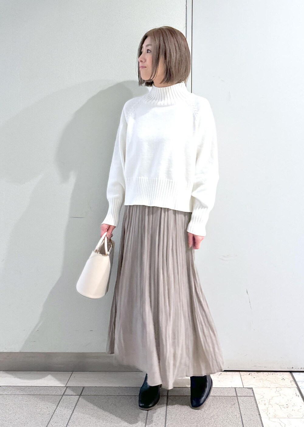 ホワイト系のニット/セーター、ブラック系のブーツ、ブラウン系のスカートを着用したレディースの冬コーディネートの5枚目の写真