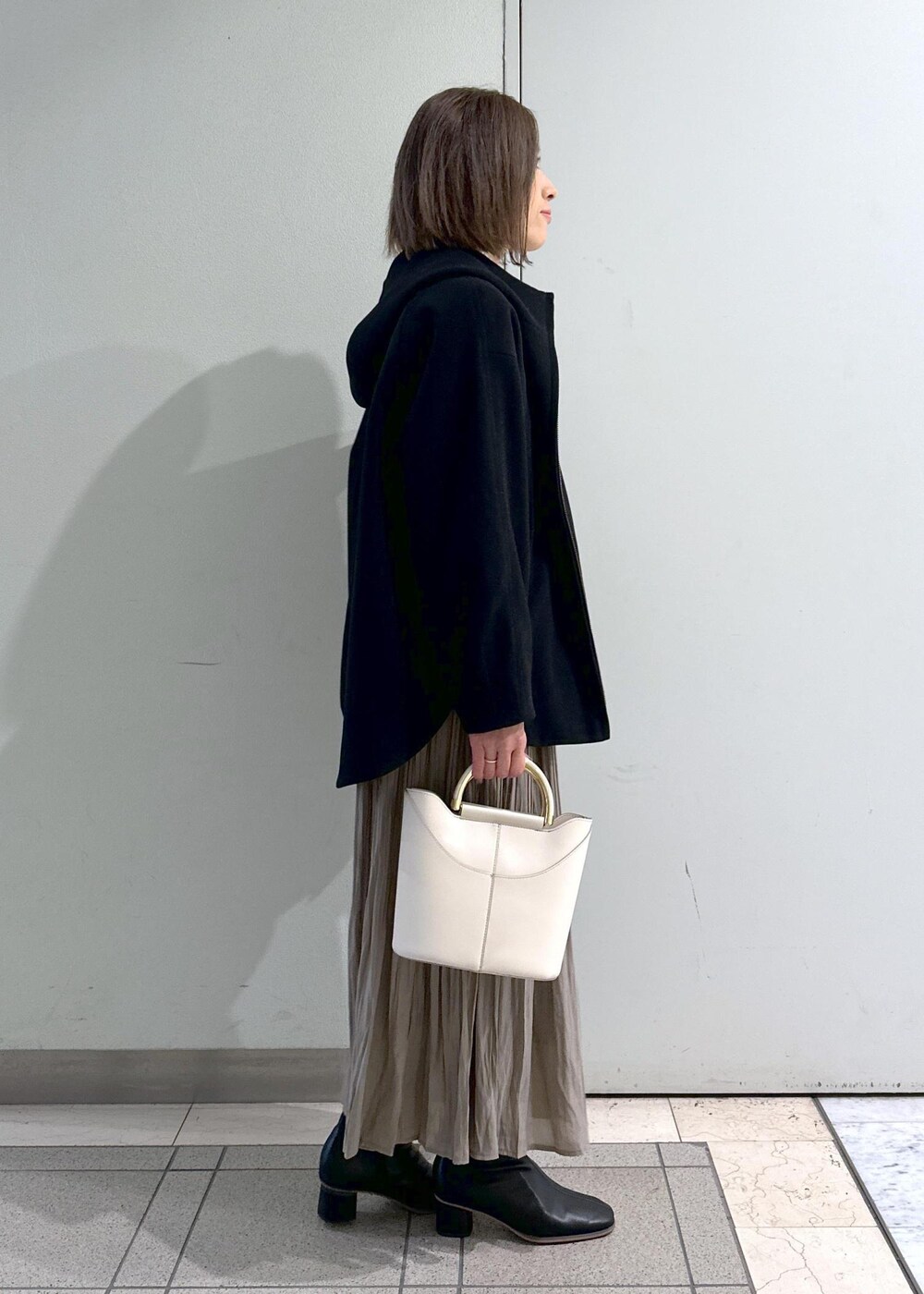 ホワイト系のニット/セーター、ブラック系のブーツ、ブラウン系のスカートを着用したレディースの冬コーディネートの4枚目の写真