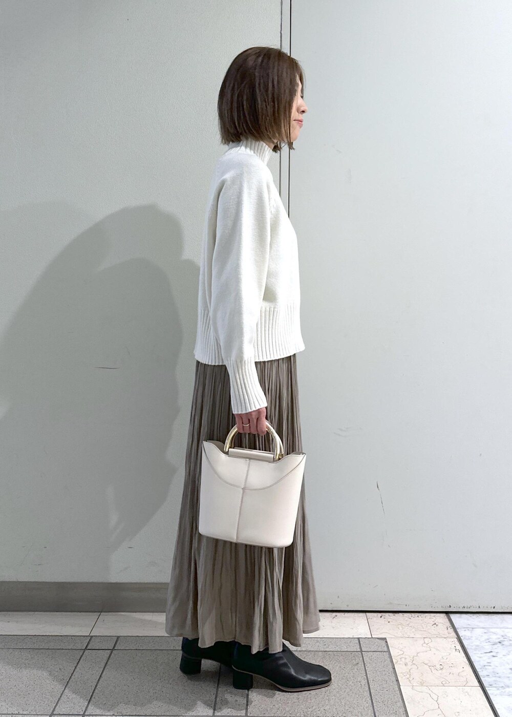 ホワイト系のニット/セーター、ブラック系のブーツ、ブラウン系のスカートを着用したレディースの冬コーディネートの8枚目の写真