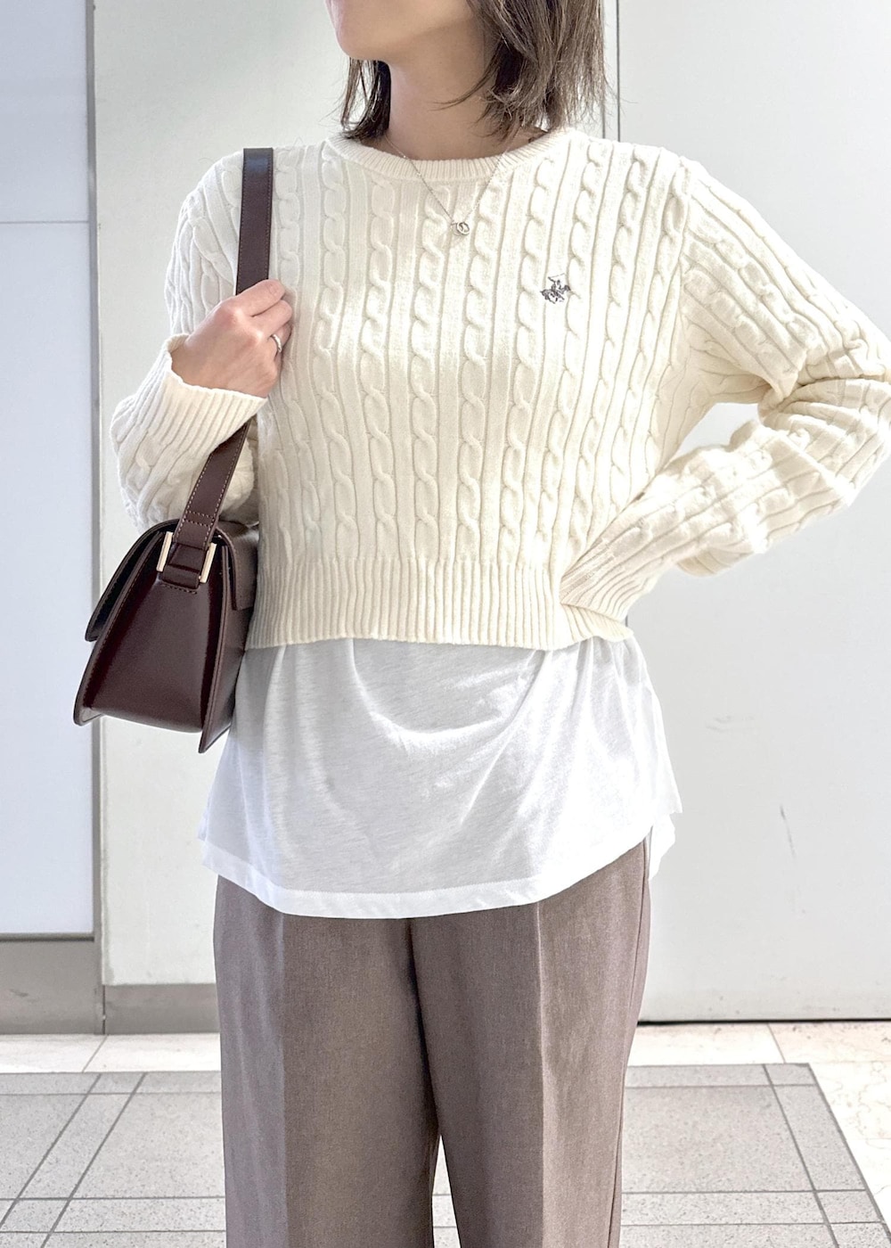 レッド系のショルダーバッグ、ベージュ系のスラックス、ホワイト系のTシャツ/カットソーを着用したレディースの冬コーディネートの6枚目の写真