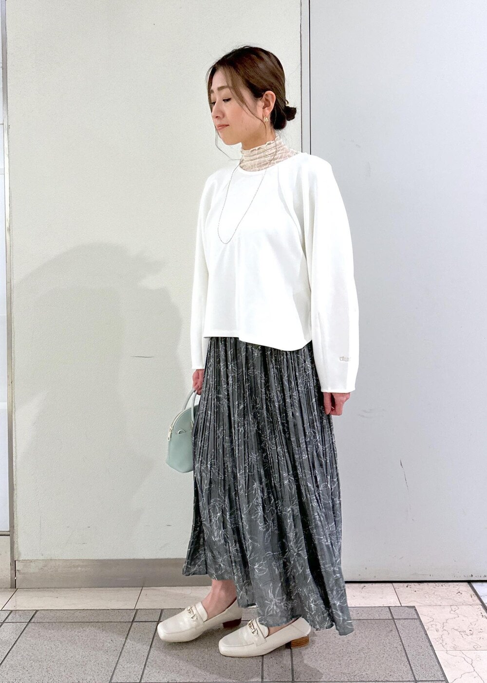 ホワイト系のTシャツ/カットソー、ホワイト系のローファー、グレー系のスカートを着用したレディースの冬コーディネートの4枚目の写真