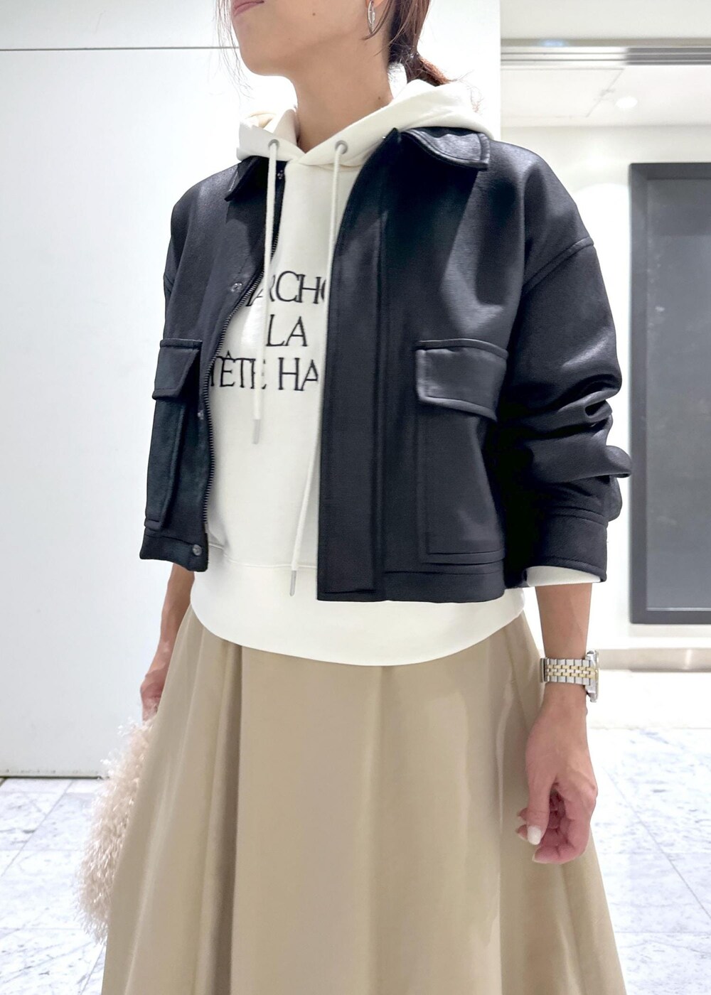 ベージュ系のハンドバッグ、ブラック系のブーツ、イエロー系のスカートを着用したレディースの秋コーディネートの9枚目の写真