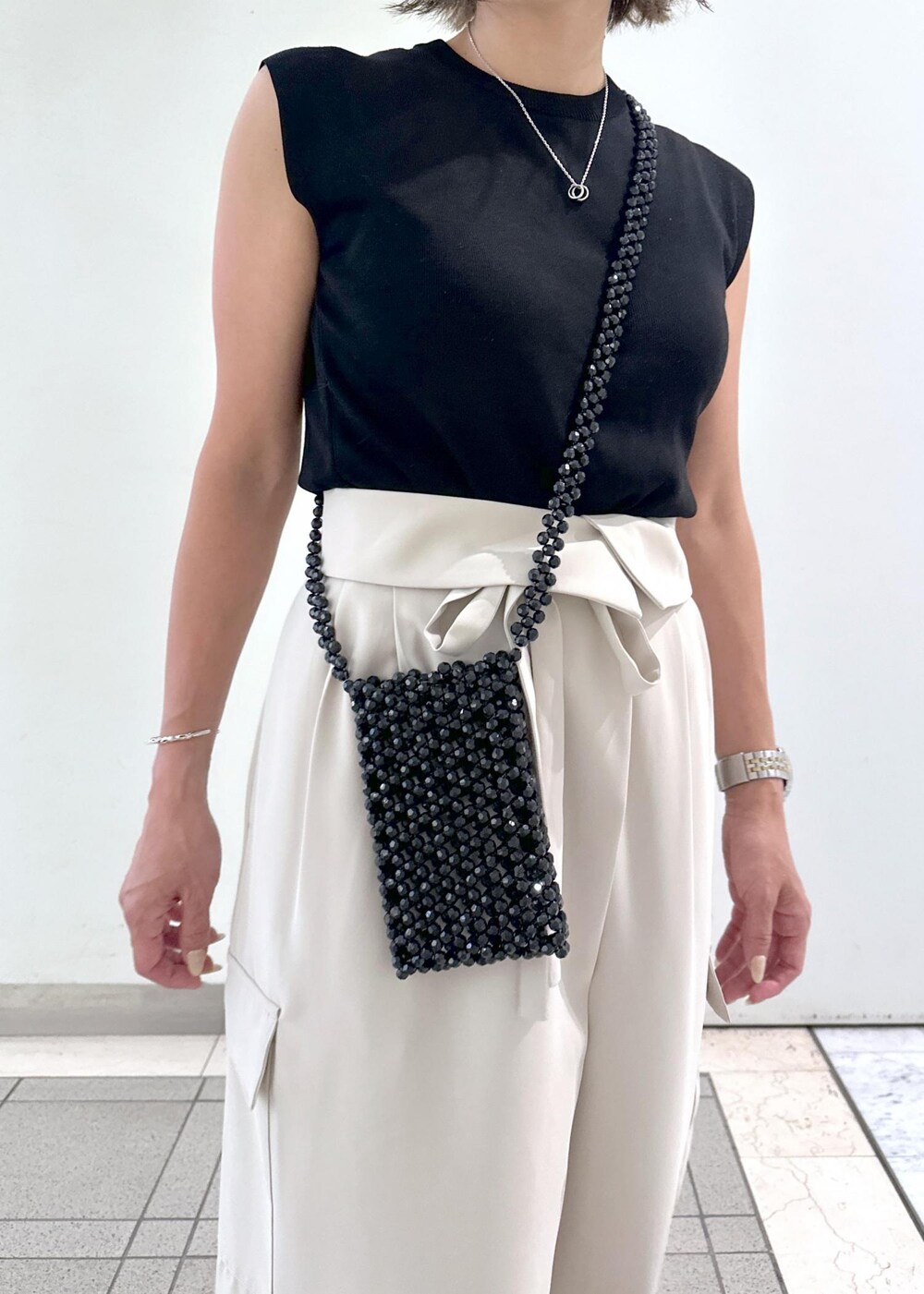 ブラック系のサンダル、ブラック系のニット/セーター、ブラック系のショルダーバッグを着用したレディースの夏コーディネートの5枚目の写真