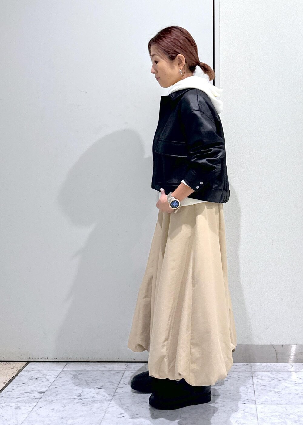 ベージュ系のハンドバッグ、ブラック系のブーツ、イエロー系のスカートを着用したレディースの秋コーディネートの6枚目の写真