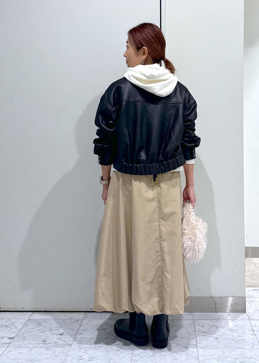 ベージュ系のハンドバッグ、ブラック系のブーツ、イエロー系のスカートを着用したレディースの秋コーディネートの7枚目の写真