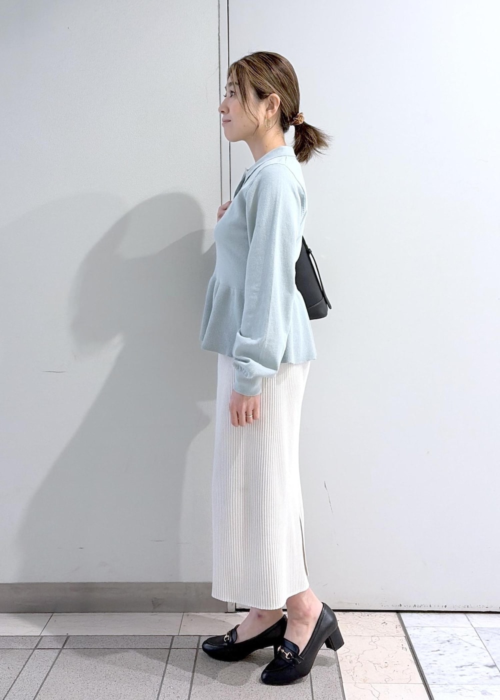 ブラック系のショルダーバッグ、ブラック系のローファー、ホワイト系のスカートを着用したレディースの春コーディネートの2枚目の写真