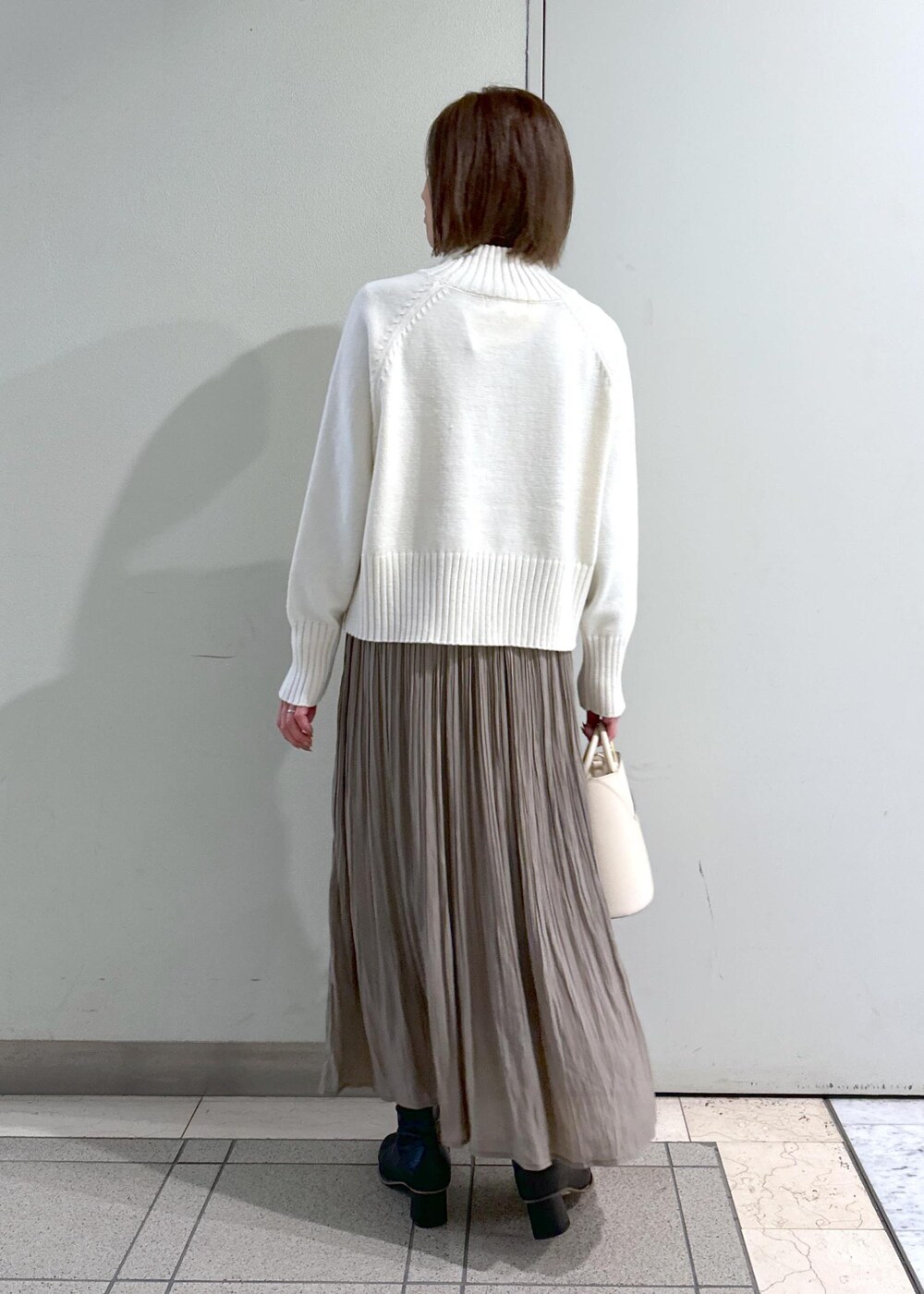 ホワイト系のニット/セーター、ブラック系のブーツ、ブラウン系のスカートを着用したレディースの冬コーディネートの7枚目の写真