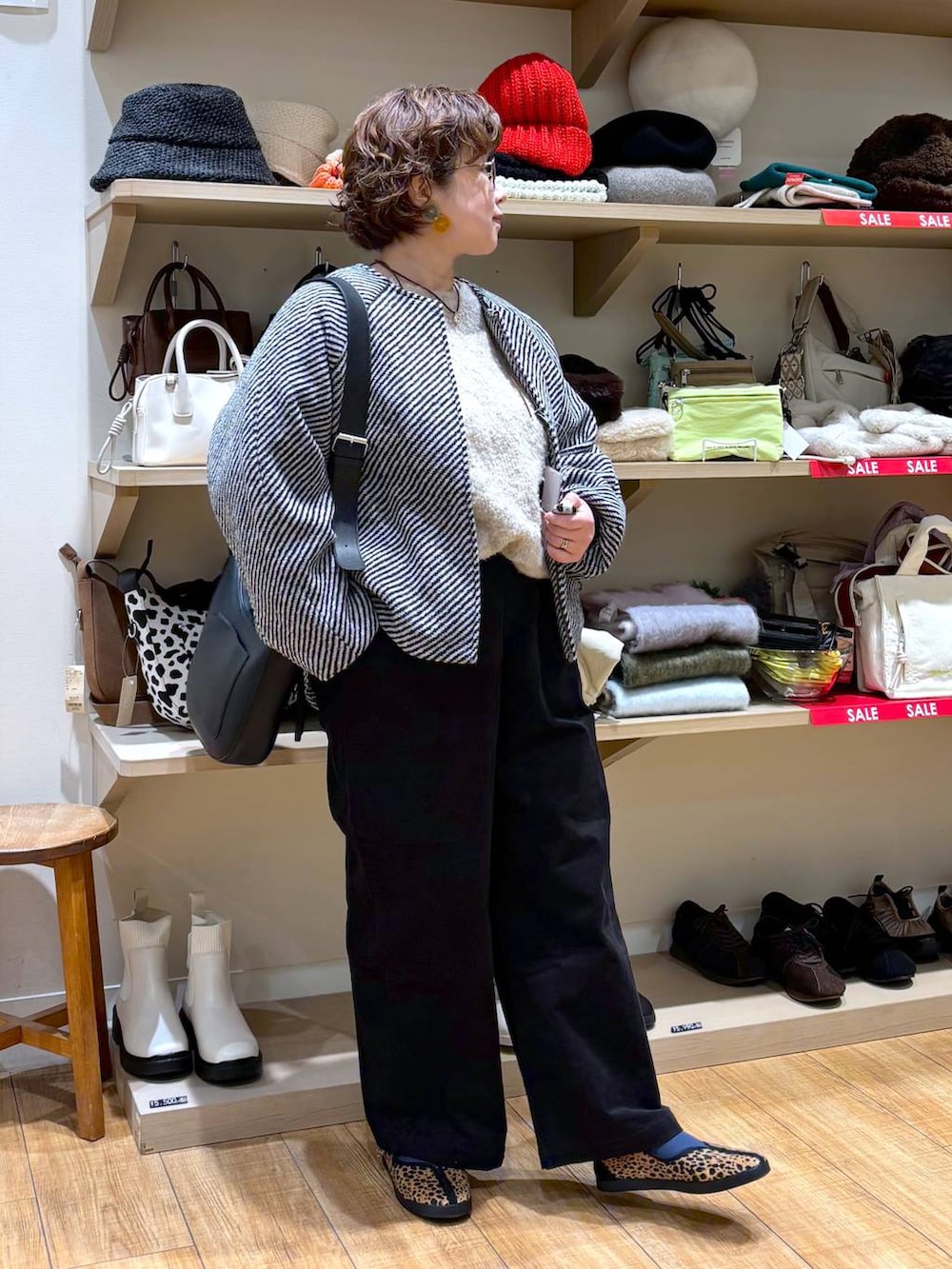 ブラック系のノーカラーコート、ブラック系のショルダーバッグ、ベージュ系のニット/セーターを着用したレディースの冬コーディネートの2枚目の写真