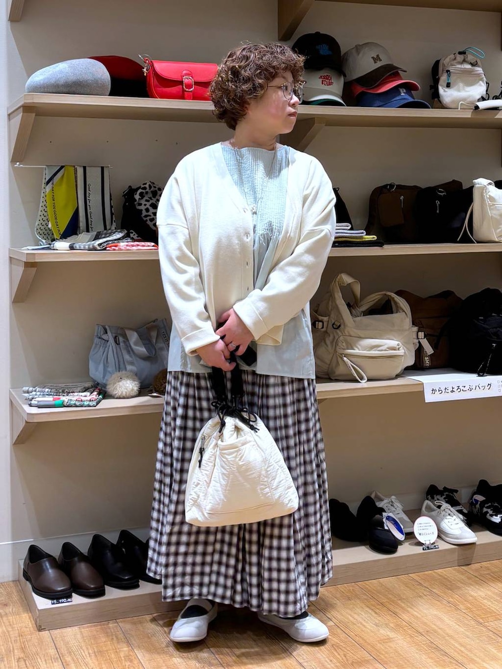 ベージュ系のショルダーバッグ、ブラウン系のスカート、ベージュ系のカーディガン/ボレロを着用したレディースの冬コーディネートの2枚目の写真