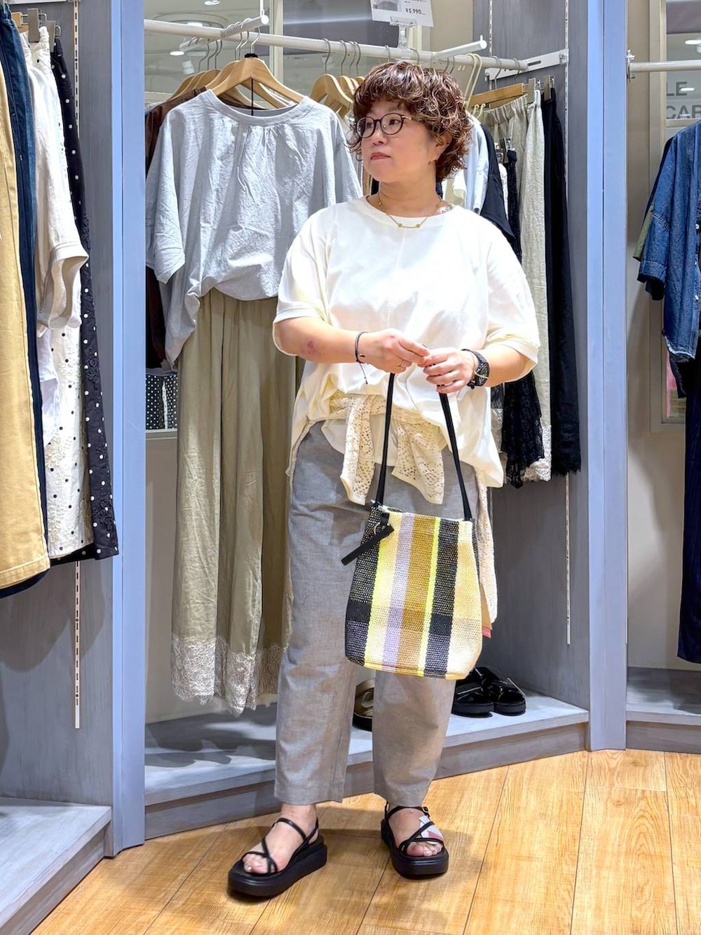 ホワイト系のTシャツ/カットソー、イエロー系のトートバッグ、ブラック系のサンダルを着用したレディースの夏コーディネートの2枚目の写真